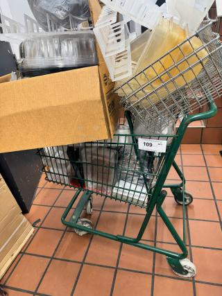 Green metal shopping cart filled with various plastic containers and a cardboard box. Auction tag shows "109" and "QTY".