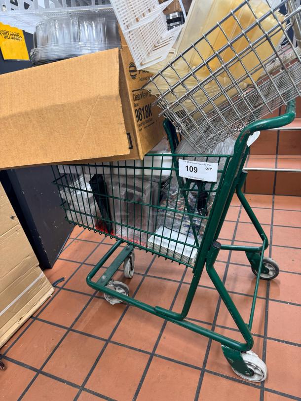 Green shopping cart with various items, including a cardboard box and plastic containers. Contents included in sale.
