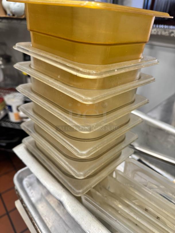 Stack of beige and yellow plastic kitchen trays, used condition, miscellaneous sizes, suitable for catering or storage.