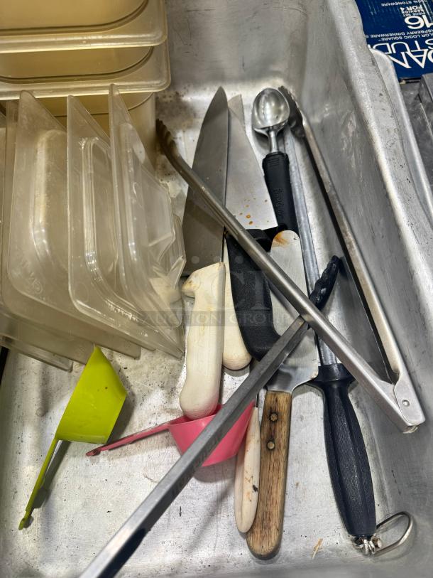 Miscellaneous kitchenware set including knives, scoops, plastic containers, tongs, and ladles in used condition.