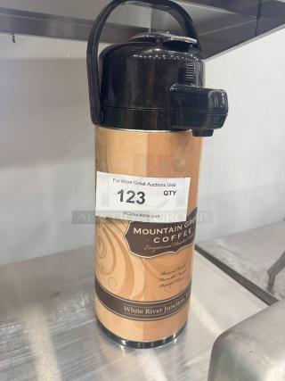 Tall coffee dispenser with black lid and handle. Label reads "Mountain Grown Coffee" from White River Junction. Auction tag number 123 visible.