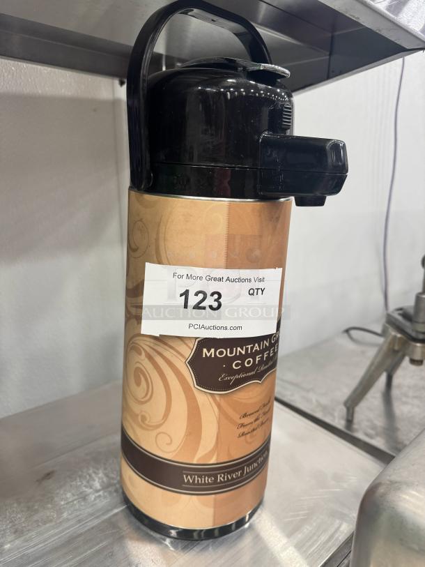 Black coffee dispenser with "Mountain Grown Coffee" label, brown design, auction tag reading "123."