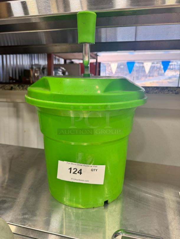 Green salad spinner with pump handle, auction label "124" attached, used condition, suitable for kitchen use.