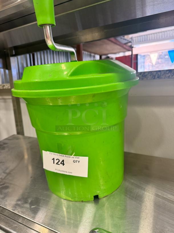 Green salad spinner with a crank handle, in used condition. Label reads "124 QTY, PCIAuctions.com."