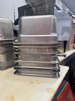Stacked stainless steel food pans, model BIDX7, with visible manufacturer markings, in good condition.