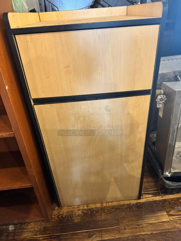 Wooden gallon waste receptacle with black trim, standing against a wooden floor. Excellent condition.