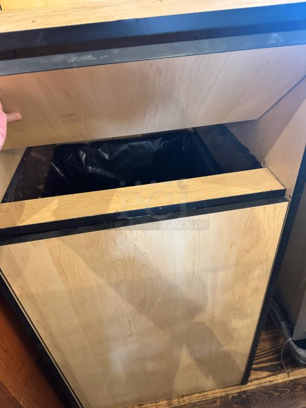 Wooden gallon waste receptacle with a hinged top, black trim, and interior plastic liner. Good condition.