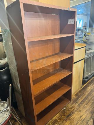 Wooden five-shelf bookcase in good condition, featuring a warm brown finish. Auction tag number 131 visible.
