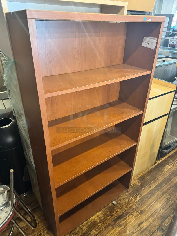 Five-shelf wooden bookcase, medium brown finish, visible wear, tag marked "131", sturdy construction.