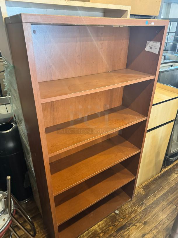 Five-shelf wooden bookcase in good condition, featuring a mid-brown finish. Ideal for home or office storage. Label marked "131".
