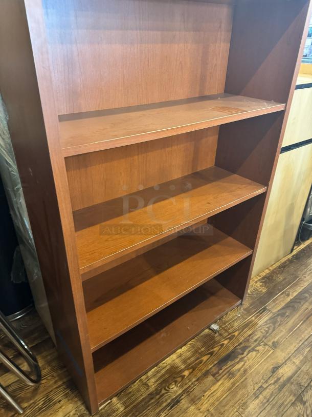 Wooden five-shelf bookcase, medium-brown finish, minor wear visible, open-back design, sturdy construction.