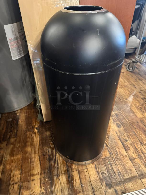 Black metal open top trash can with a dome lid, minor surface scratches, standing on wooden floor.