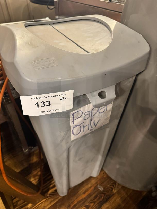 Rubbermaid trash can, gray, labeled "Paper Only," with visible usage wear. Auction tag number 133 attached.