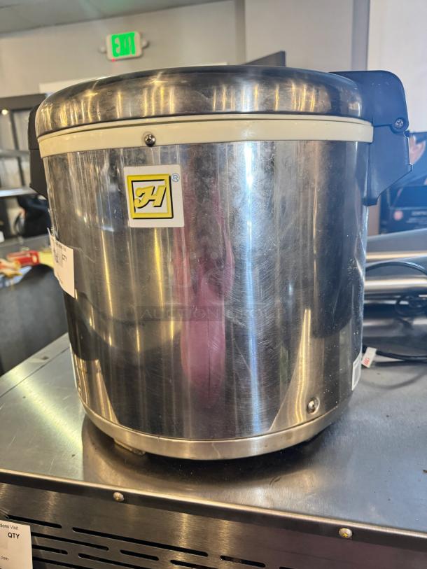 Stainless steel rice warmer, 50-cup capacity, brushed finish, visible brand logo, good condition, sturdy black handles.