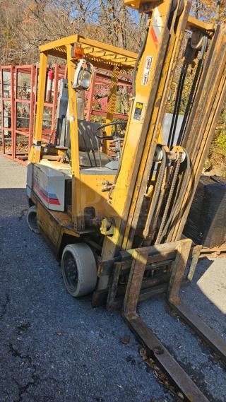 KOMATSU FG 15ST-2 forklift in good condition, yellow with visible wear. Features lifting mechanism and sturdy wheels.