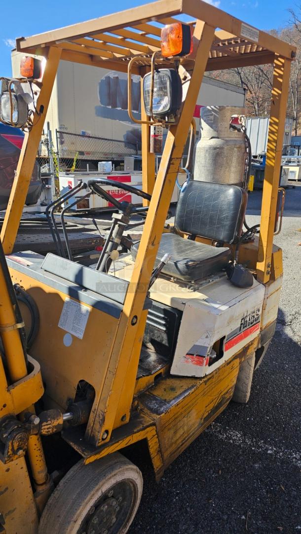 KOMATSU FG 15ST-2 forklift, yellow, good condition, LPG tank, protective frame, seat wear visible, functional controls.