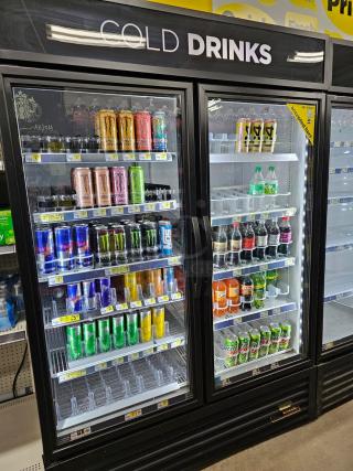 TRUE GDM-49 commercial glass door merchandiser refrigerator, tested and working, stocked with assorted beverages.