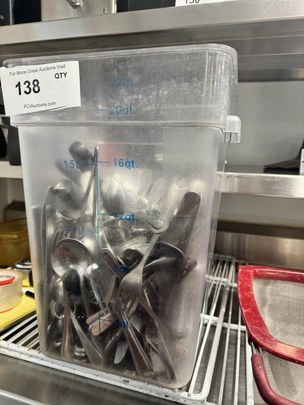 Lot of stainless steel cutlery in a clear container marked with quart measurements. Contains forks, spoons, and knives.