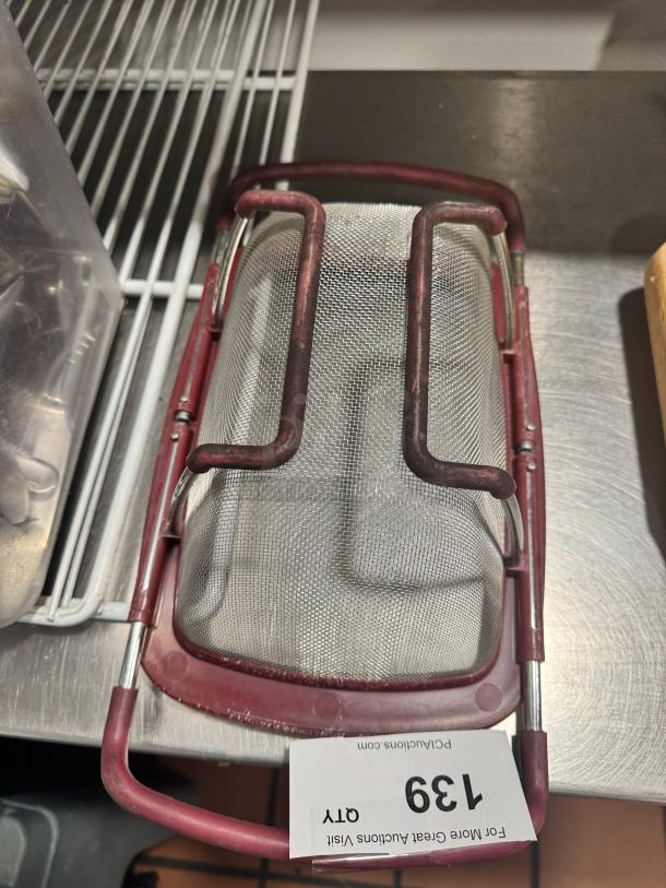 Expandable metal colander with red plastic handles, in good condition. Auction tag labeled "139" attached.