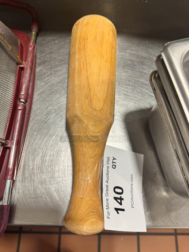 Wood muddler with smooth finish, used for cocktail making. Auction tag reads "140" and "PCI Auctions."