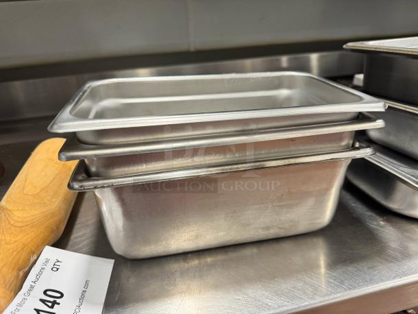 Lot of 3 stainless steel food pans, used, with slightly worn edges. Auction tag with lot number visible.