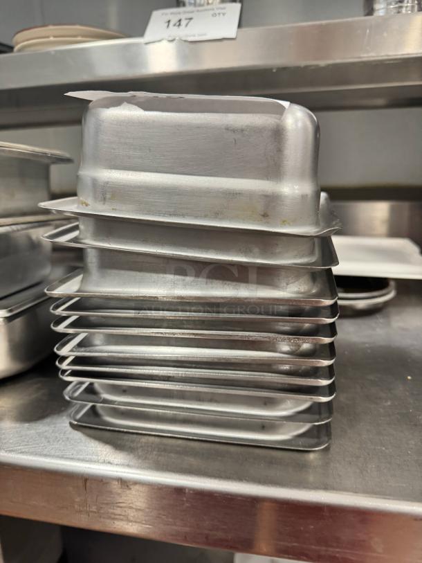 Stainless steel food pans BIDX10, stacked, minor wear, solid construction, ideal for kitchen use. Auction lot 147.