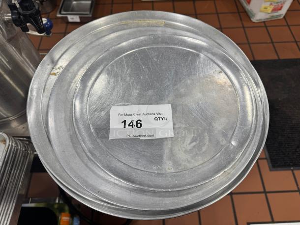 Set of 4 metal pizza pans, used condition, label showing auction lot number 146 from PCI Auctions.