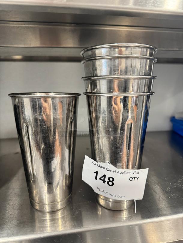 Set of stainless steel mixer cups, model BIDX5, in good condition. Quantity label shows "148 QTY." Ideal for commercial use.