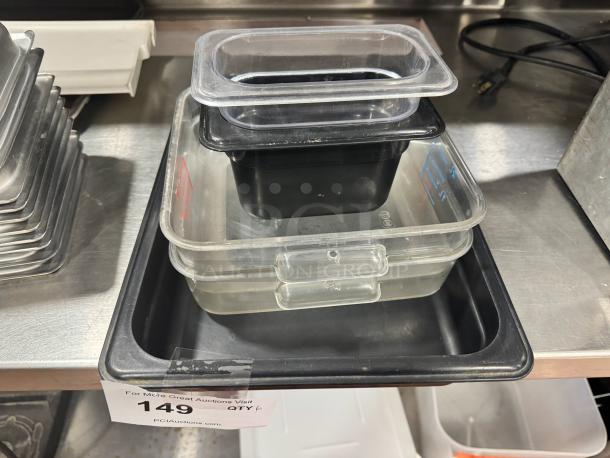 Lot of 6 plastic food pans, stacked, various sizes, clear and black. Used condition, auction tag with lot number 149 visible.