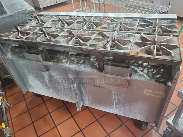 Imperial NG 10 burner stove with 2 ovens, metallic finish, visible wear, industrial-grade, caster wheels for mobility.