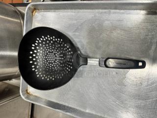 Farberware skimmer with black perforated head and ergonomic handle, modest wear. Branded handle reads "FARBERWARE."