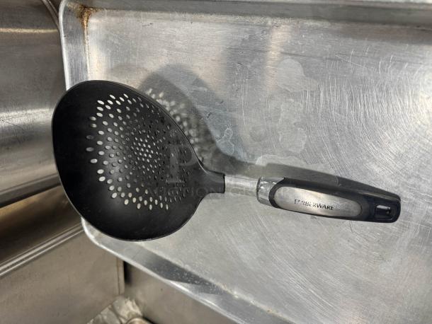Farberware skimmer with black perforated head and handle, metal accent, and visible brand marking. Good condition.