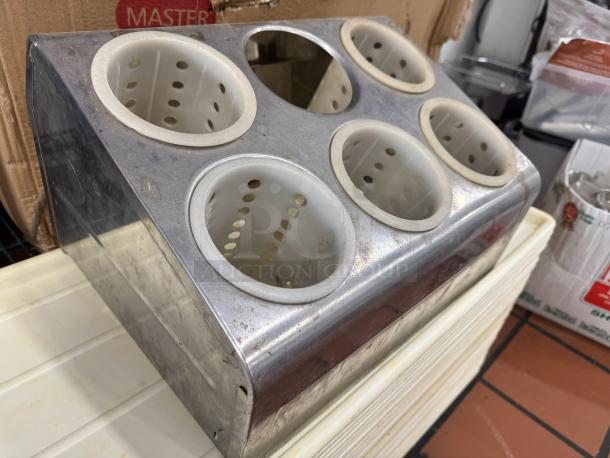 Six-hole stainless steel flatware organizer, includes five perforated plastic cylinders, one cylinder missing, slight wear.