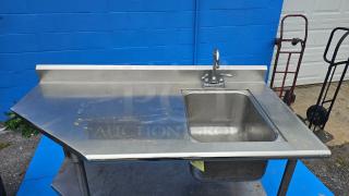 Stainless steel work table with integrated sink. Needs faucet repair. Visible wear on surface. Ideal for commercial use.