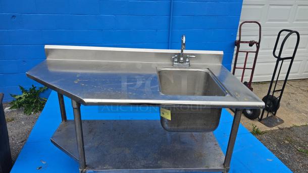 Stainless steel work table with integrated sink needing faucet repair, sturdy build, used condition, ideal for commercial kitchens.