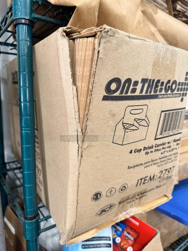 Cardboard box of 4 cup drink carriers with handle from "On The Go." Box is slightly worn. Item number 2797 visible.