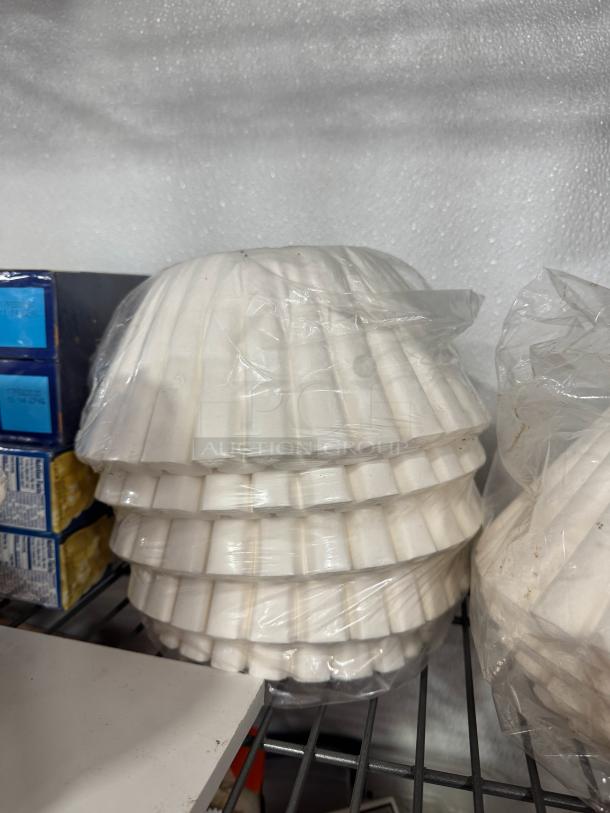 Stack of white coffee filters wrapped in plastic, placed on a metal shelf.
