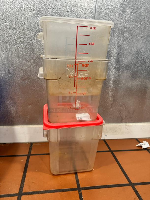 Lot of 3 clear plastic food storage containers, varying capacity up to 8 Qt, red lids, used condition, measurement markings visible.