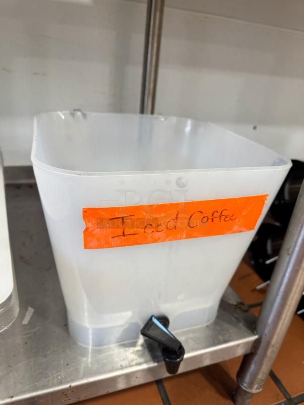 Plastic beverage dispenser, missing lid, labeled "Iced Coffee." Features pour spout, square shape, used condition.