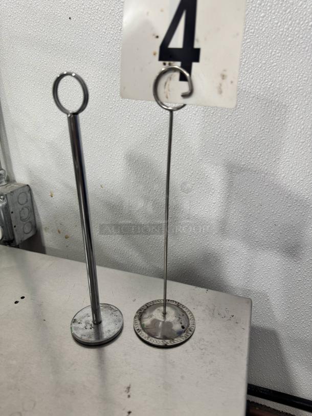 Lot of 26 metal table card holders, round base with vertical wire and loop. Slight wear, used condition.