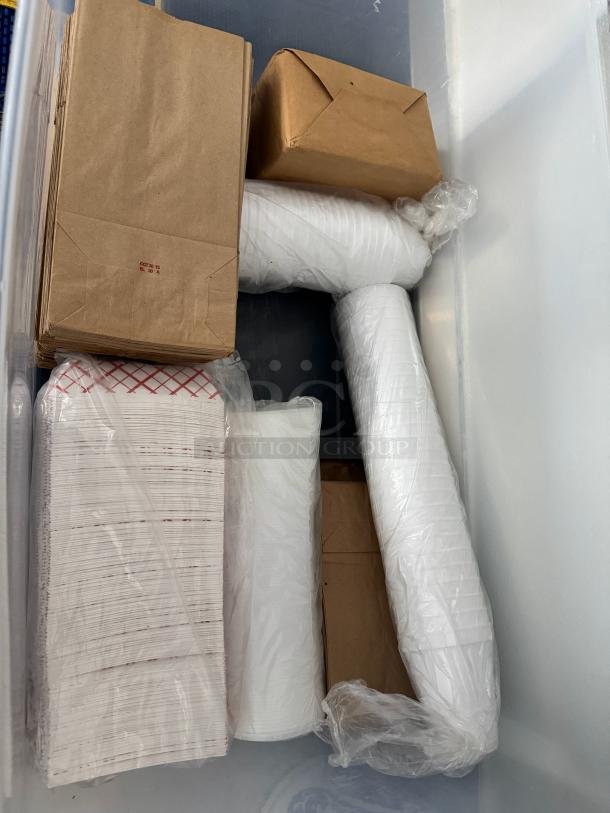 Lot of disposable food supplies including paper bags, cups, and containers in original packaging. Suitable for bulk use.