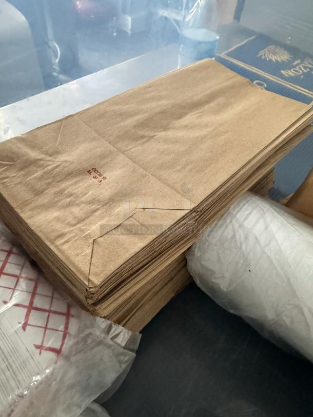 Lot of disposable food supplies, including brown paper bags in bulk. Visible stamp: "No. 25" with red text.