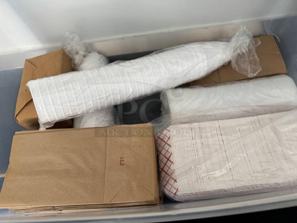 Lot of disposable food supplies in a plastic bin, including brown paper bags and white paper trays, in new condition.