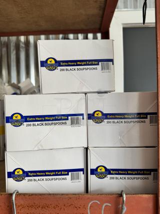 Boxes of Sunset Extra Heavy Weight Full Size black soup spoons, 200 per box, stacked on a shelf. Label shows "Made in China."