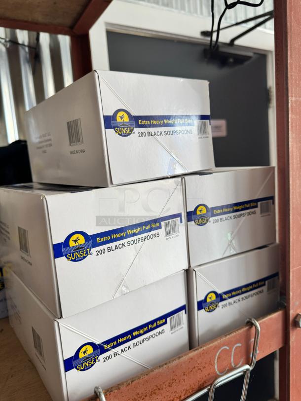 Box of 200 black soup spoons by Sunset, extra heavy weight full size, made in China, stacked on shelf.