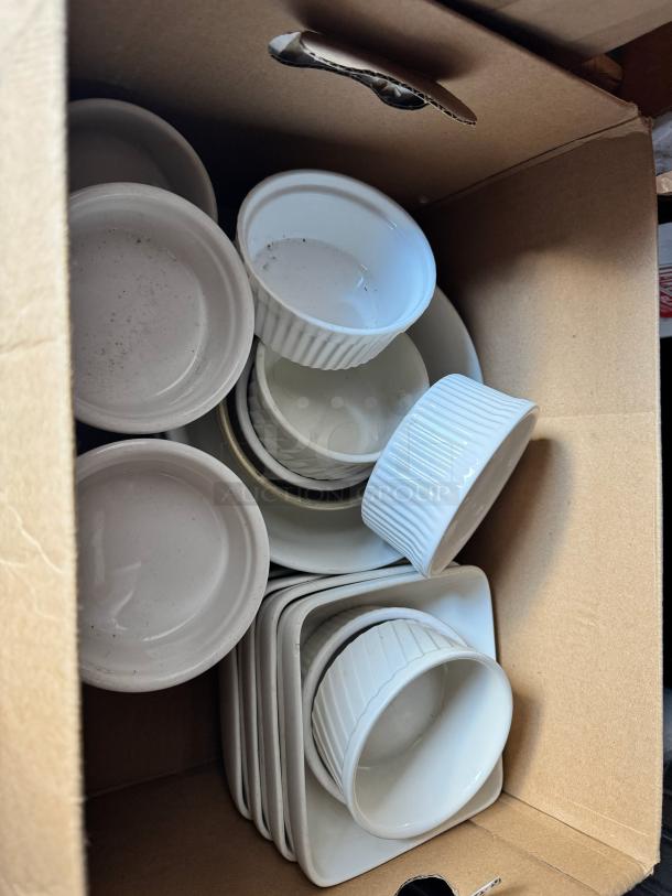 Box of miscellaneous white porcelain dishes, including ramekins and square plates, in used condition.