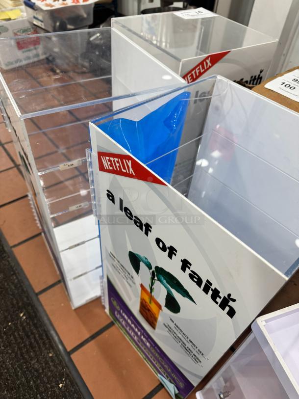 Acrylic Display Cabinet BIDX3 with clear shelves. Features "Netflix" branding and promotional signage. Good condition.