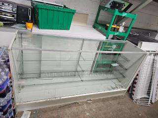 6ft glass display case BIDX2, with three shelves, metal frame, minor wear visible, suitable for retail or exhibition use.