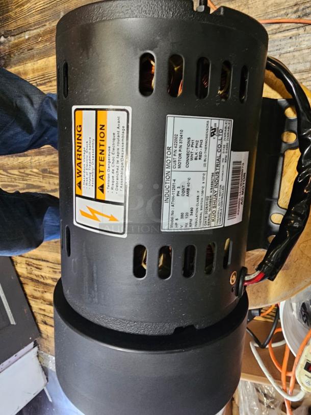 Brand new induction motor ATHH-112M1-4, 3-phase; black casing with visible warning and specification labels.