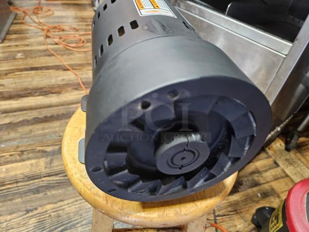 Brand new INDUCTION MOTOR ATHH-112M1-4, 3-phase, black finish. Label shows model and specifications, placed on wooden stool.